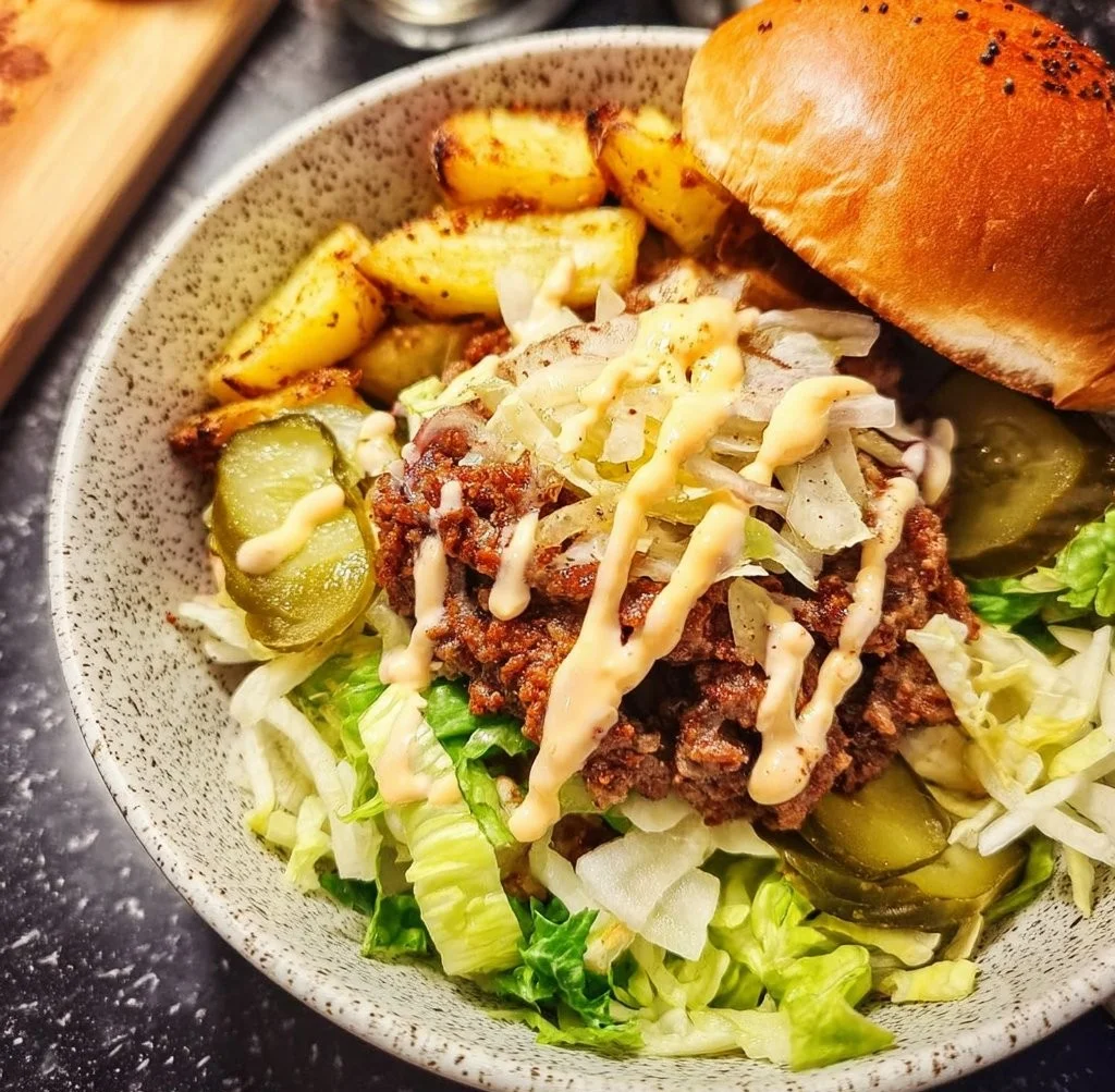 A colorful burger bowl filled with fresh ingredients and toppings.